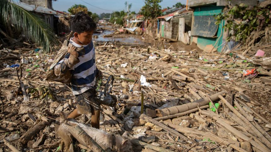 Boy & dog cross
their destroyed village following Typhoon Vamco